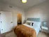 Bright, chic bedroom with plush bed, stylish headboard, and cozy decor, offering a peaceful retreat in modern living space.
