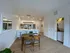 Contemporary apartment kitchen and dining area with sleek white cabinetry, modern appliances, and elegant seating, boasting natural wood flooring and a convenient in-unit laundry space.