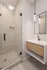 Elegant bathroom with a sleek glass-enclosed shower and modern floating vanity featuring chic pendant lighting.