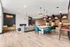 Chic and modern apartment lounge with elegant lighting, plush seating, and stylish dining area featuring vibrant teal chairs on wood flooring.