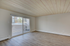 Bright, open-concept room with sleek wood flooring and expansive sliding glass doors leading to a private balcony.