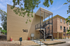 Charming brick apartment building with external black metal staircase and lush green surroundings at number 140.