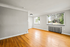 Bright and airy living area with large windows, gleaming hardwood floors, and modern lighting.