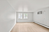 Bright and airy living room with sleek wood flooring, large window for natural light, and modern air conditioning.