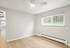 Bright and inviting room with large window, sleek ceiling fan, and elegant wooden flooring, perfect for a cozy living space.