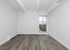 Bright, modern apartment interior with sleek hardwood floors, large window, and fresh white walls offering a serene and stylish space.