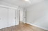 Bright and airy bedroom with elegant wood flooring and modern white closet doors, offering a fresh and welcoming atmosphere.