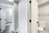 Sleek apartment hallway showcasing modern minimalist design with pristine doors leading to a bright room and chic bathroom.