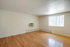 Bright, cozy room featuring elegant hardwood floors, a large window, and an efficient wall-mounted air conditioning unit.