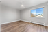 Bright and modern room with large window, stylish wood flooring, and ceiling fan creating an inviting atmosphere.