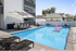 Modern outdoor pool area featuring a sparkling swimming pool, pink flamingo float, stylish lounge chairs, and a shaded dining space ideal for relaxation and entertaining.