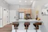Modern kitchen with sleek bar stools, elegant pendant lighting, stainless steel appliances, and a stylish countertop.