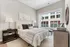 Elegant bedroom with a plush bed and contemporary decor, featuring a large window offering city views.