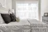 Bright and elegant bedroom with a cozy bed, stylish pillows, and large window with urban view.