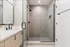 Modern bathroom featuring a sleek glass shower enclosure, stylish black fixtures, and a spacious vanity with elegant wood cabinetry.