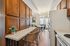 Charming kitchen with wooden cabinetry, breakfast bar, and elegant lighting leading to a cozy dining area with balcony access.