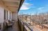 Inviting balcony with cozy chairs offering picturesque street views and a serene natural backdrop.