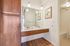 Elegant bathroom with double sinks, large mirror, and ambient pendant lighting, complemented by warm wooden cabinetry and sleek flooring.