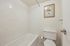 Bright bathroom with classic white tiles, featuring a bathtub and framed botanical art for a serene vibe.