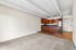 Inviting open-plan living area with plush carpet and a sleek modern kitchen featuring rich wood cabinetry and stainless steel appliances.