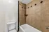Modern bathroom showcasing elegant tiled walls, a pristine bathtub, and a sleek toilet for a refined ambiance.