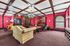 Elegant living space with vintage charm, featuring ornate wood paneling, luxurious red wallpaper, a plush sofa, and a classic chandelier.