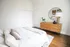 Old Town Chicago, IL, Apartments Near Oak Street Beach - 1537 N Orleans - A Bright Minimalist Bedroom With A Neatly Made Bed, A Wooden Dresser, A Round Mirror, And White Closet Doors.