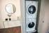 Old Town Chicago, IL, Apartments Near Second City Comedy Club - 1537 N Orleans - A Compact Laundry Area With A Stacked Washer And Dryer Next To A Glass Console Table.
