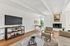 Inviting living area with elegant modern decor, featuring a cozy seating arrangement, sleek fireplace, and a stylish workspace flooded with natural light.