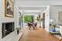 Charming living area featuring a cozy white brick fireplace, elegant dining space with lush green views, and modern decor.