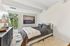 Bright and modern bedroom with plush bedding, soft rug, and large window offering scenic views.