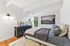 Elegant bedroom with modern decor, featuring a cozy bed with plush pillows, a stylish dresser, and a large window offering natural light.