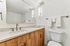Elegant bathroom featuring a modern vanity with wooden cabinets, sleek countertop, and large mirror with stylish lighting.