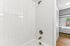 Bright bathroom featuring elegant white tile and modern fixtures, adjacent to a cozy bedroom with natural light.