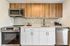 Speer, CO, Apartments Near Arlington Park - El Greco Apartments - Modern Kitchen With Wood and White Cabinets, Quartz-Look Counters, Stainless Steel Appliances, and Tile Backsplash.