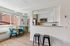 Bright and modern kitchen with sleek white cabinets, stainless steel appliances, and a cozy dining nook with vibrant teal chairs.