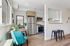 Modern kitchen with stainless steel appliances, elegant wooden cabinets, and a cozy dining nook with a stylish teal chair.