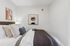 Cozy and stylish bedroom with modern art on white walls, featuring a plush bed adorned with elegant pillows and soft linens.