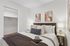 Cozy bedroom featuring a plush bed with decorative pillows, stylish artwork, and soft ambient lighting, perfect for relaxation.