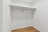 Spacious walk-in closet with sleek wooden flooring and modern shelving, perfect for organized storage.