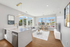 Bright and modern open-plan living area with a sleek kitchen island, elegant decor, and large windows offering vibrant city views.