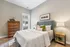 Cozy bedroom with elegant decor, featuring a stylish upholstered bed, crisp white linens, and accent pillows, complemented by chic wooden dressers and soft lighting.