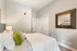 Elegant bedroom with plush pillows, large mirror, and sleek design creating a cozy, inviting atmosphere.