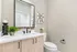 Elegant bathroom with modern fixtures, featuring a sleek vanity with double faucets, large mirror, and tasteful decor accents.