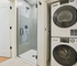 Modern bathroom with sleek glass shower and convenient in-unit stacked washer and dryer.