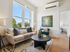Bright and inviting living room with large windows, minimalist decor, and a cozy seating arrangement.
