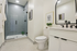 Elegant modern bathroom featuring a glass-enclosed shower with stylish tiles, sleek vanity with double faucets, and tasteful decor.