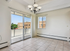 Bright and airy room with elegant chandelier and sliding glass doors opening to a scenic balcony view.