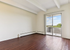 Bright, empty room featuring elegant hardwood flooring and large sliding glass door opening to a scenic balcony view.