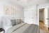 Chic bedroom with modern art, cozy bed, and sleek white closet doors, offering tranquil vibes in contemporary living.